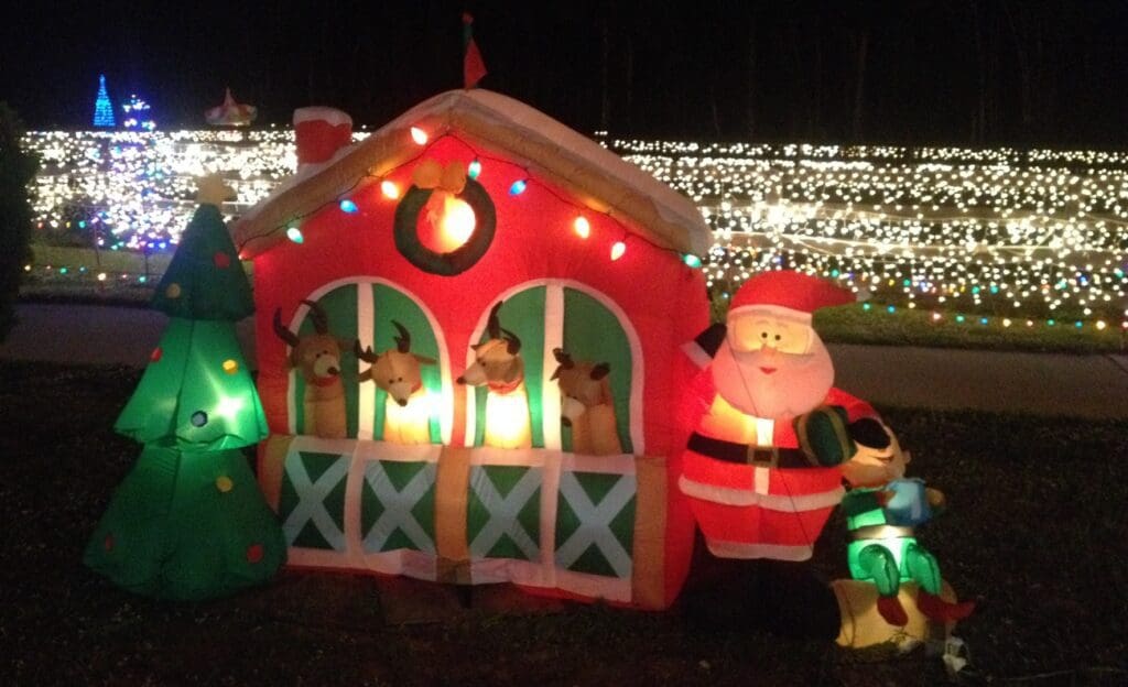 Inflatable Santa and reindeer in a festive house at night.