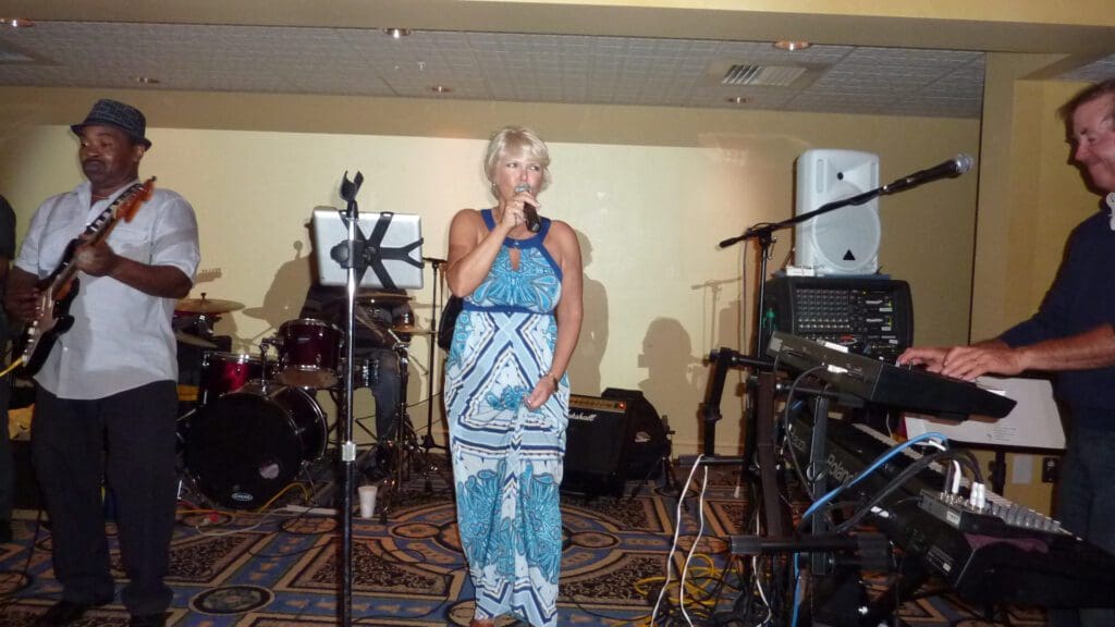 Woman singing on stage with microphone and musical instruments in background.