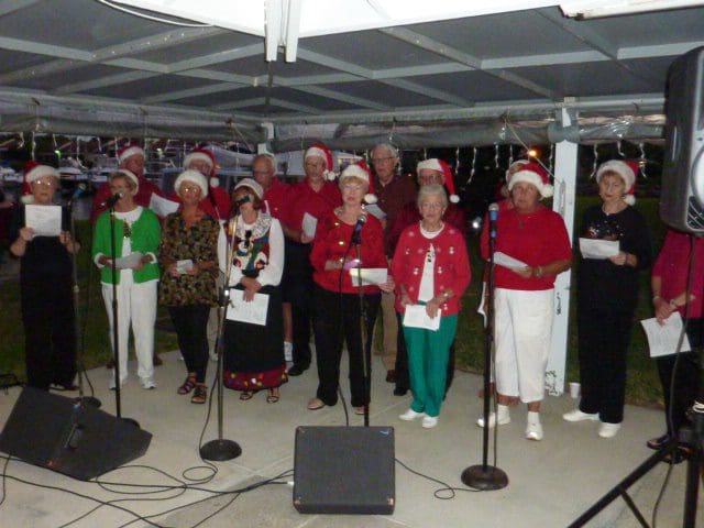 A festive group of elderly people singing together under a decorated canopy.