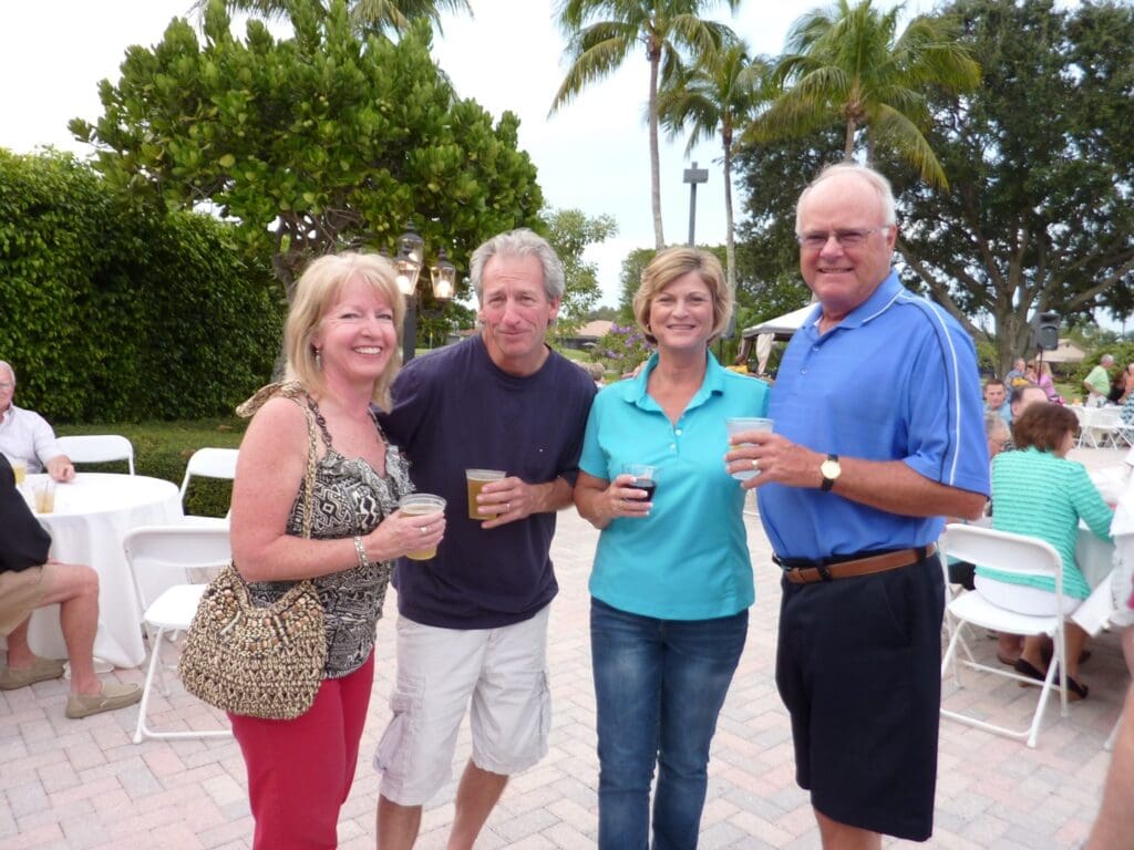 Four adults enjoying drinks outdoors on a sunny day.