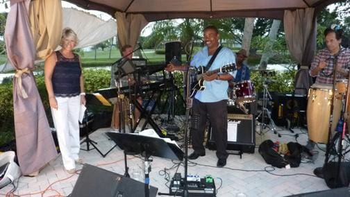 Band performing live on an outdoor stage with musical instruments.