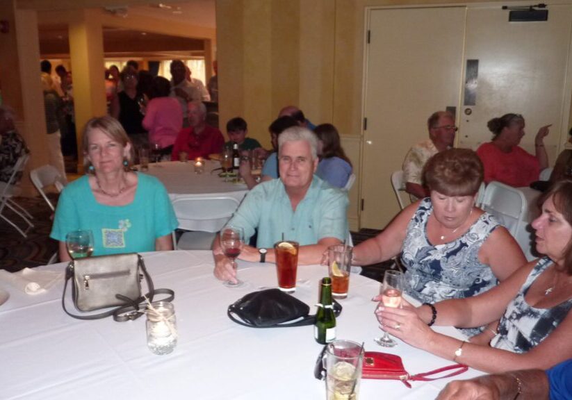 Three women sitting at a table in a social gathering.
