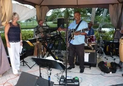 Band performing live on an outdoor stage with musical instruments.